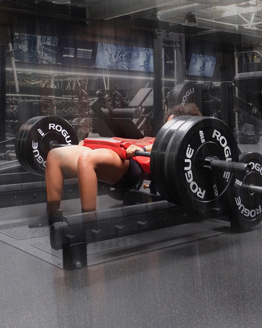 woman doing heavy hip thrusts using uppper barbell pad