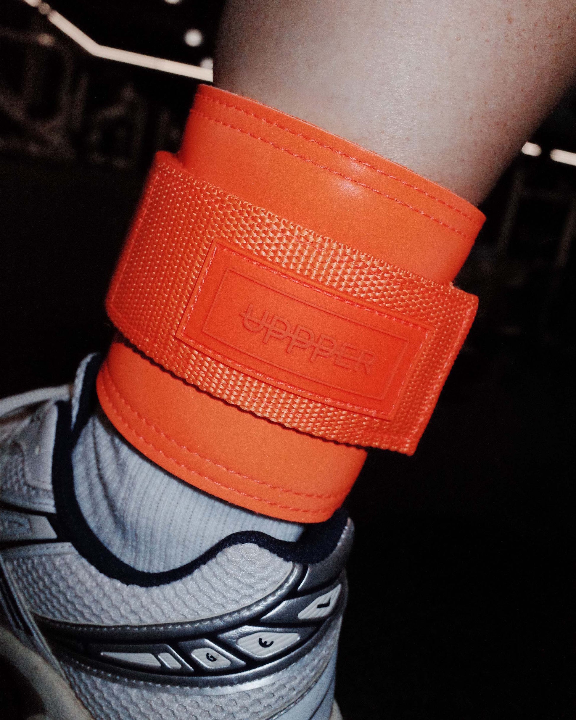 neon orange uppper ankle strap with brand logo on a person's ankle