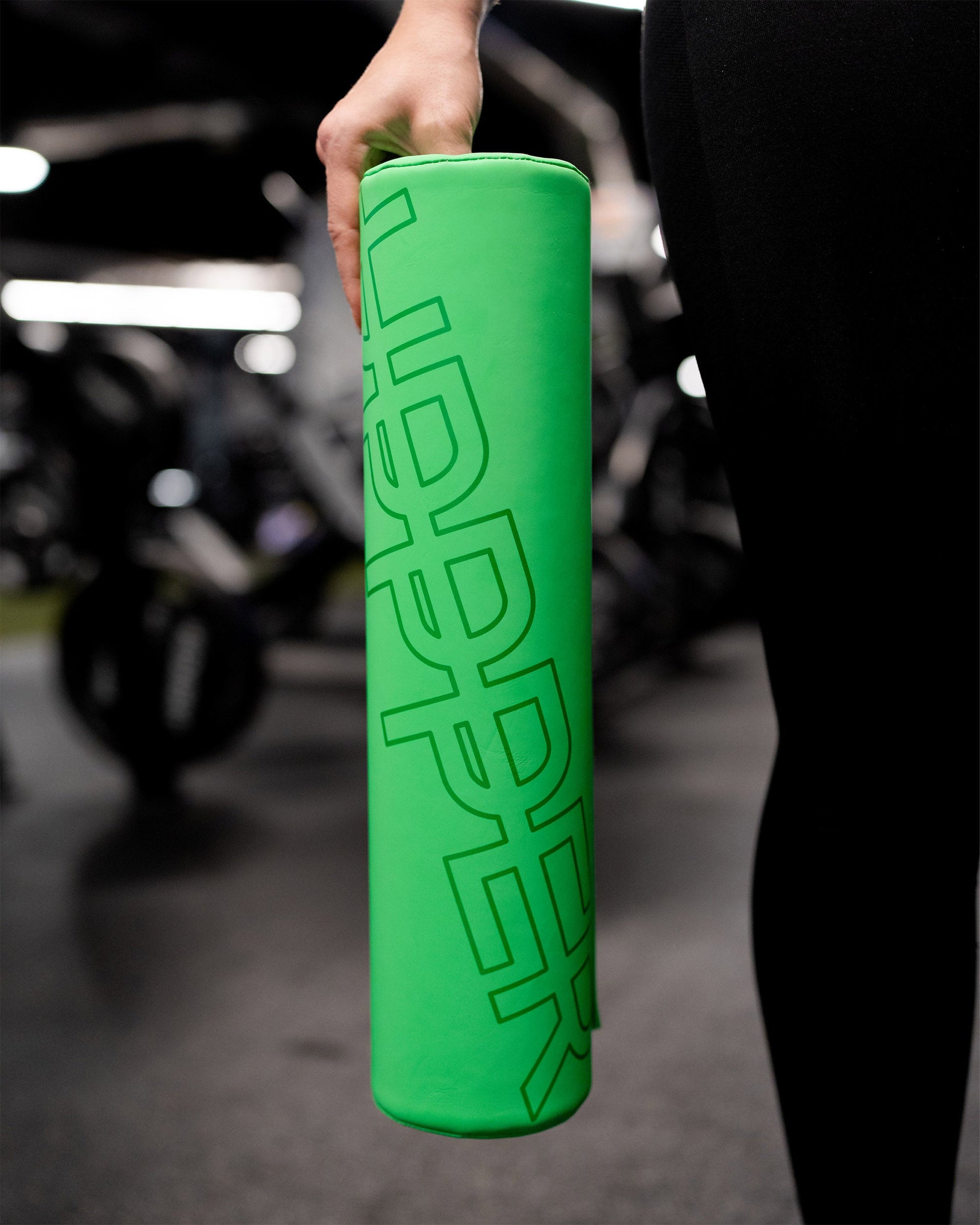 hand holding neon green uppper barbell pad with logo showing
