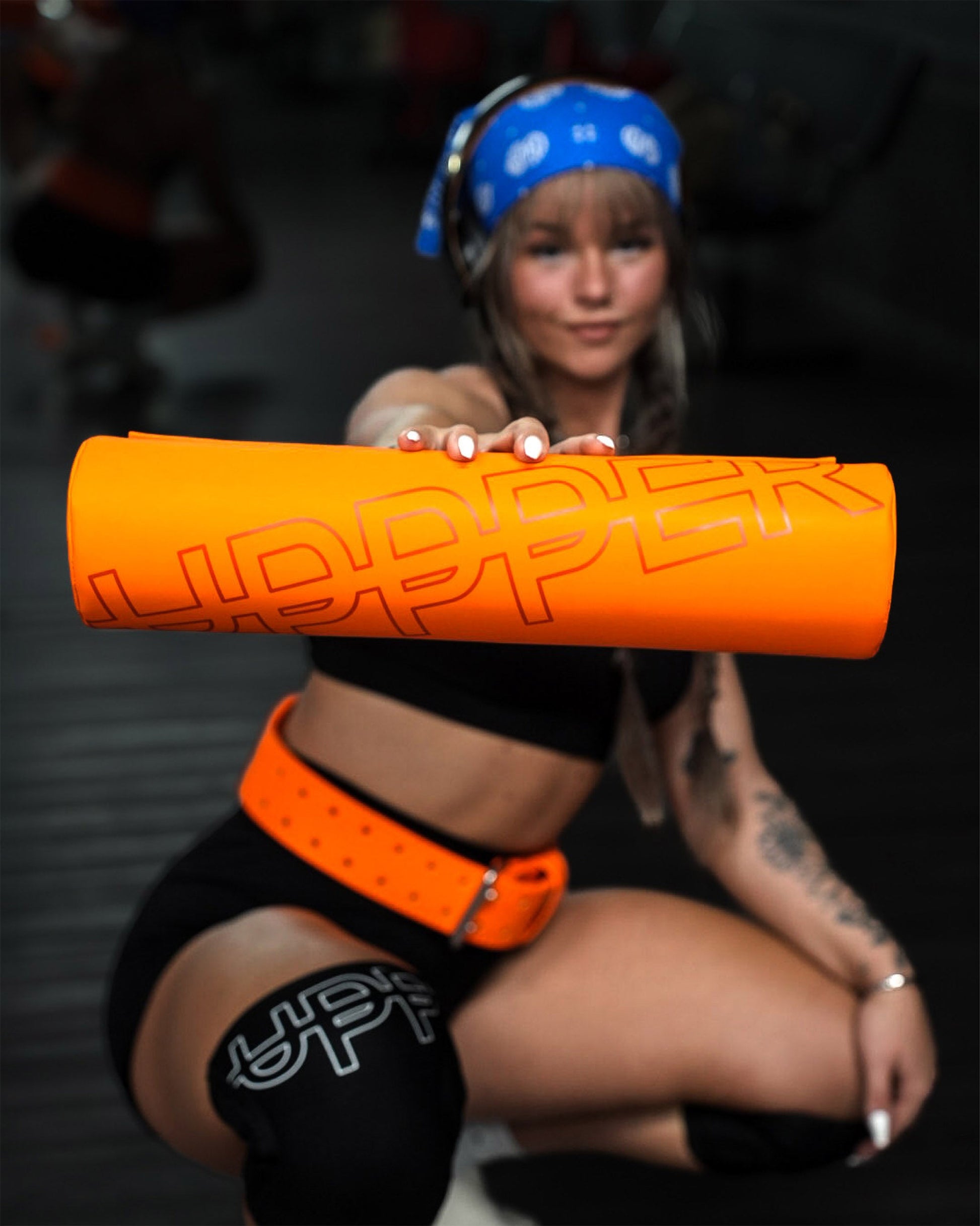 close-up of neon orange uppper barbell pad showing logo lifestyle shot in gym