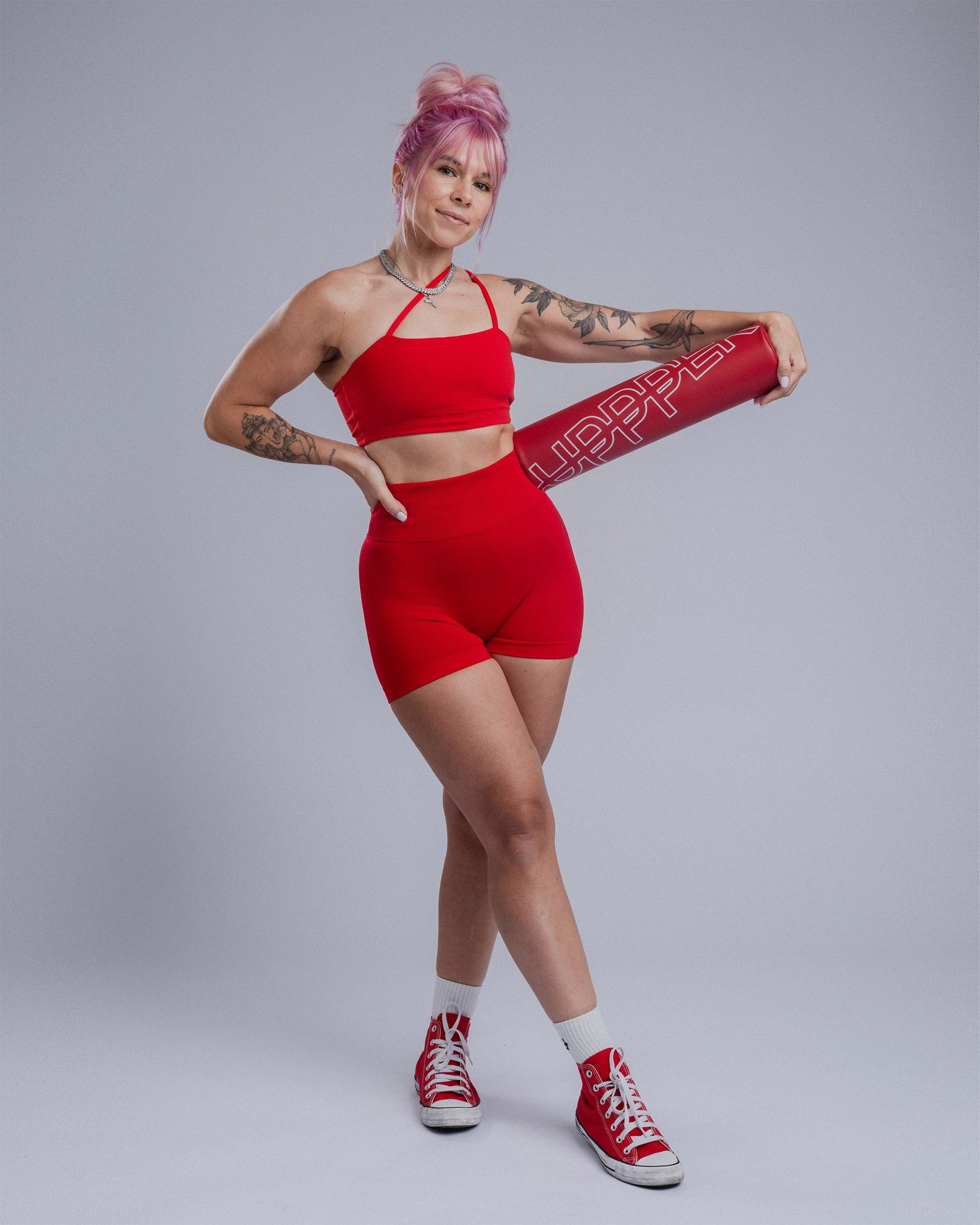 athlete posing with red uppper barbell pad showing logo - studio shoton grey backgrond