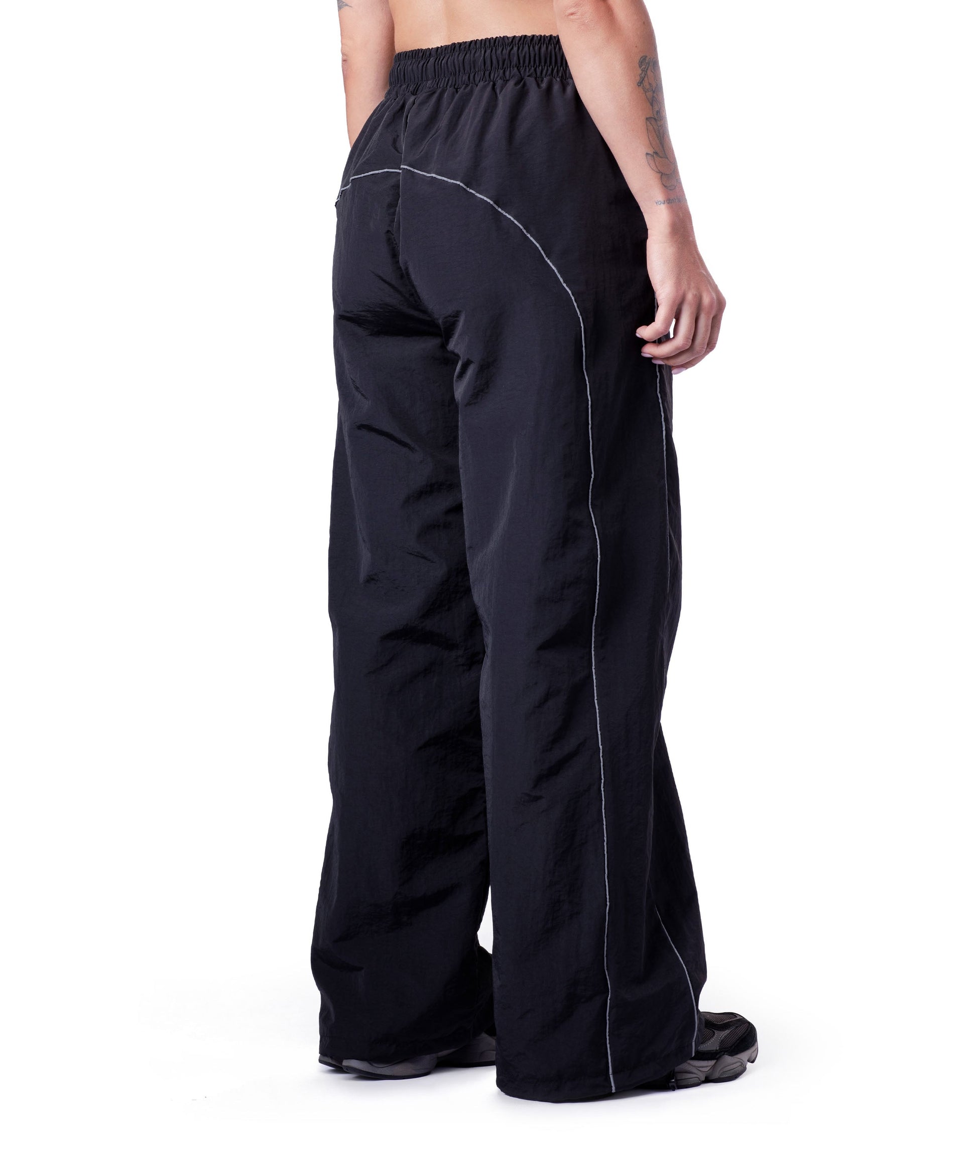 back of black uppper track pants showing reflective lines on white background