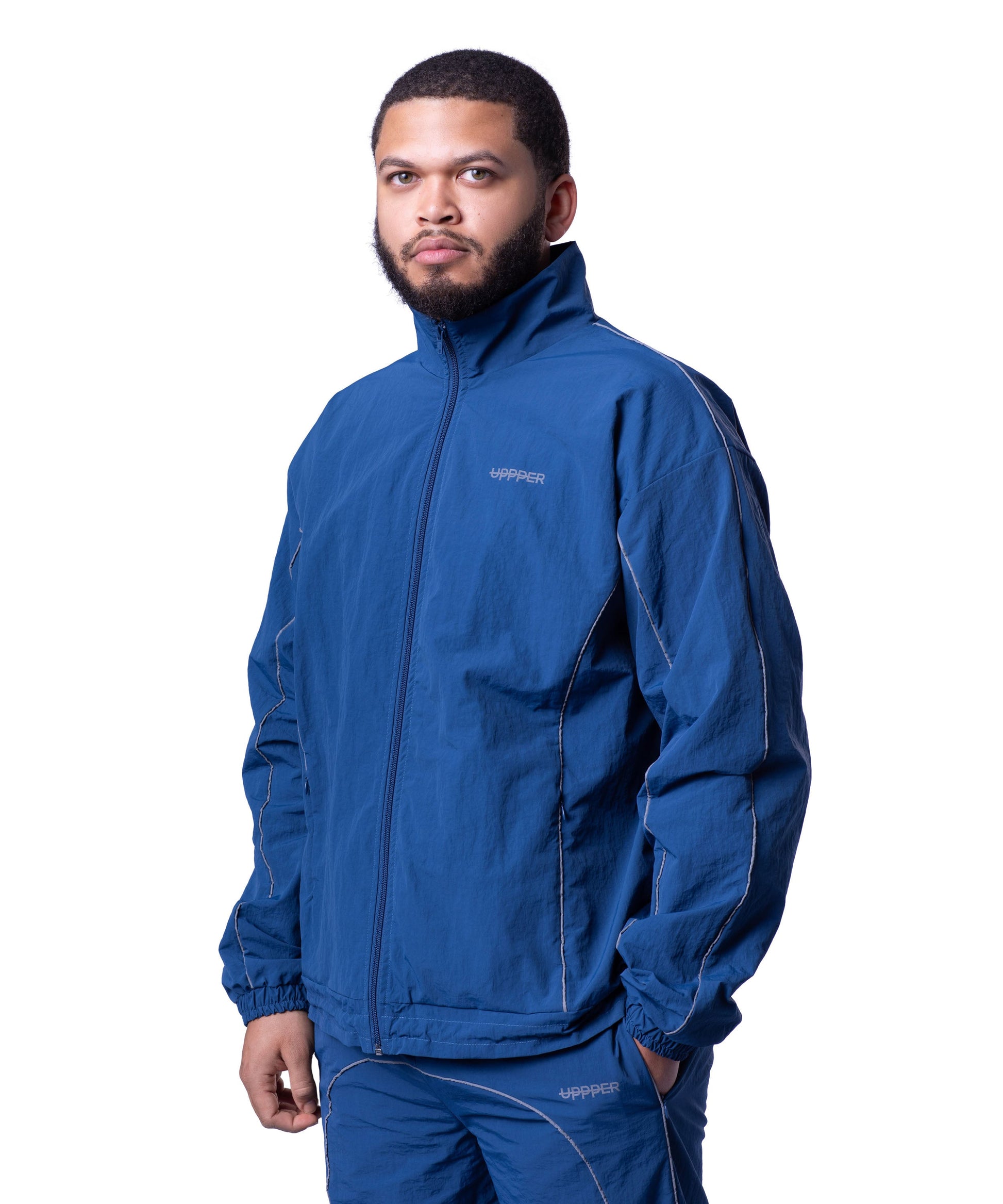 front of blue uppper track jacket with reflective stripe detail on white background