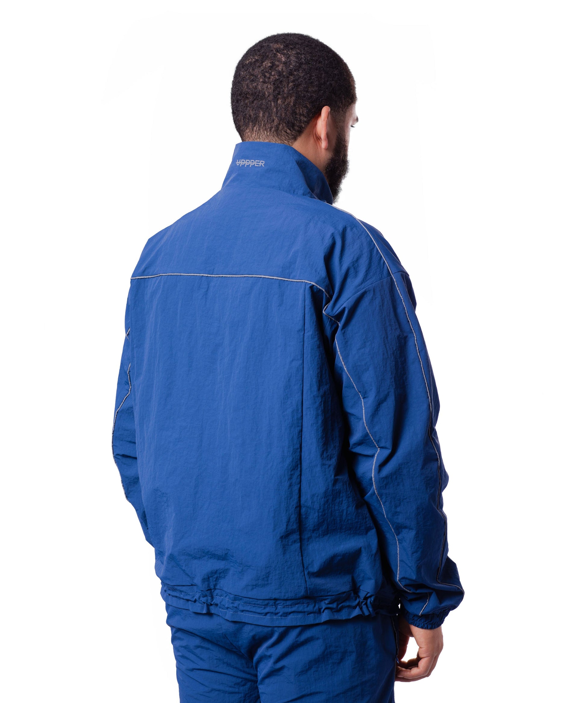 back of blue uppper track jacket showing reflective lines on white background