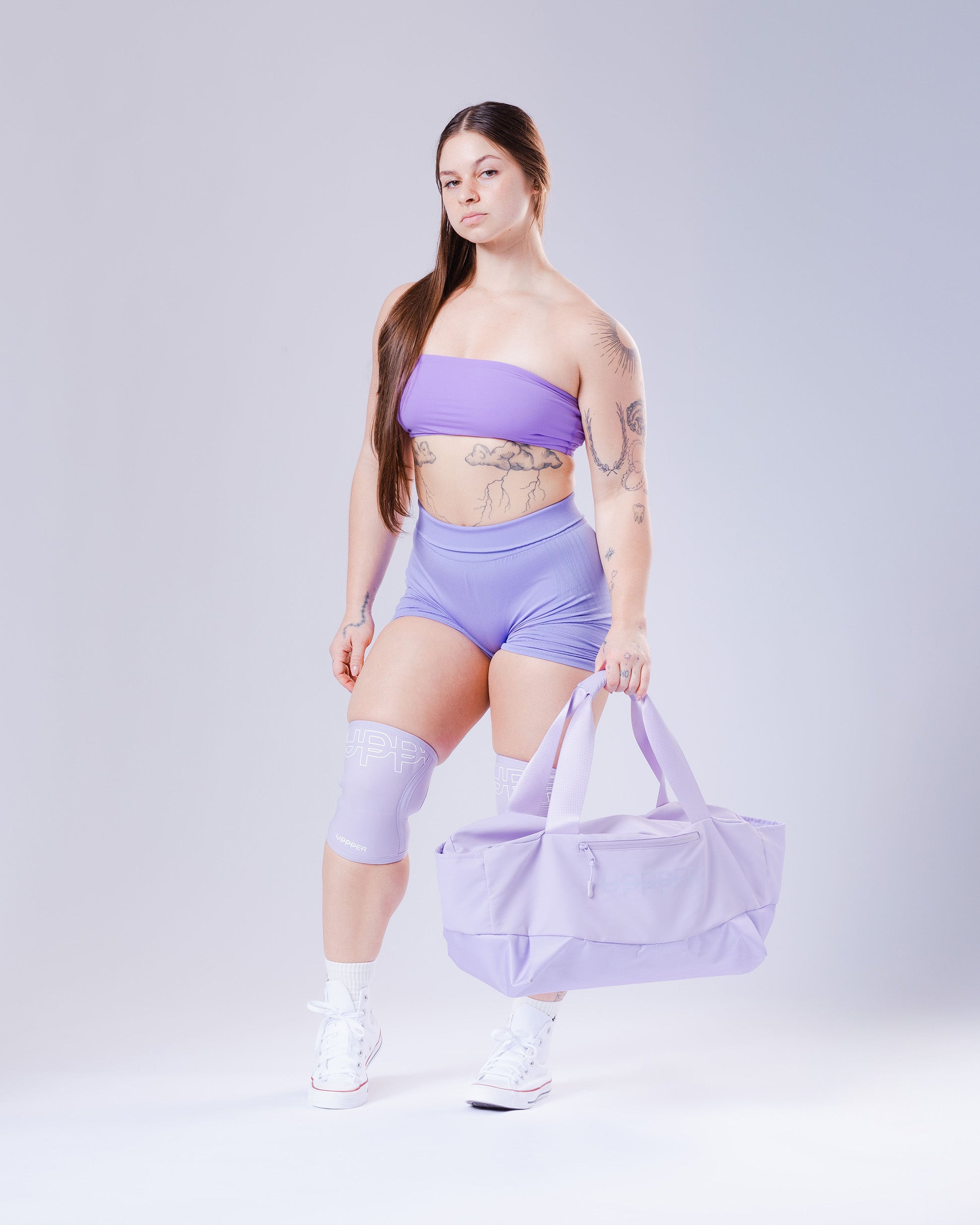 model wearing lavender uppper knee sleeves with a matching uppper duffle bag on a light gray background