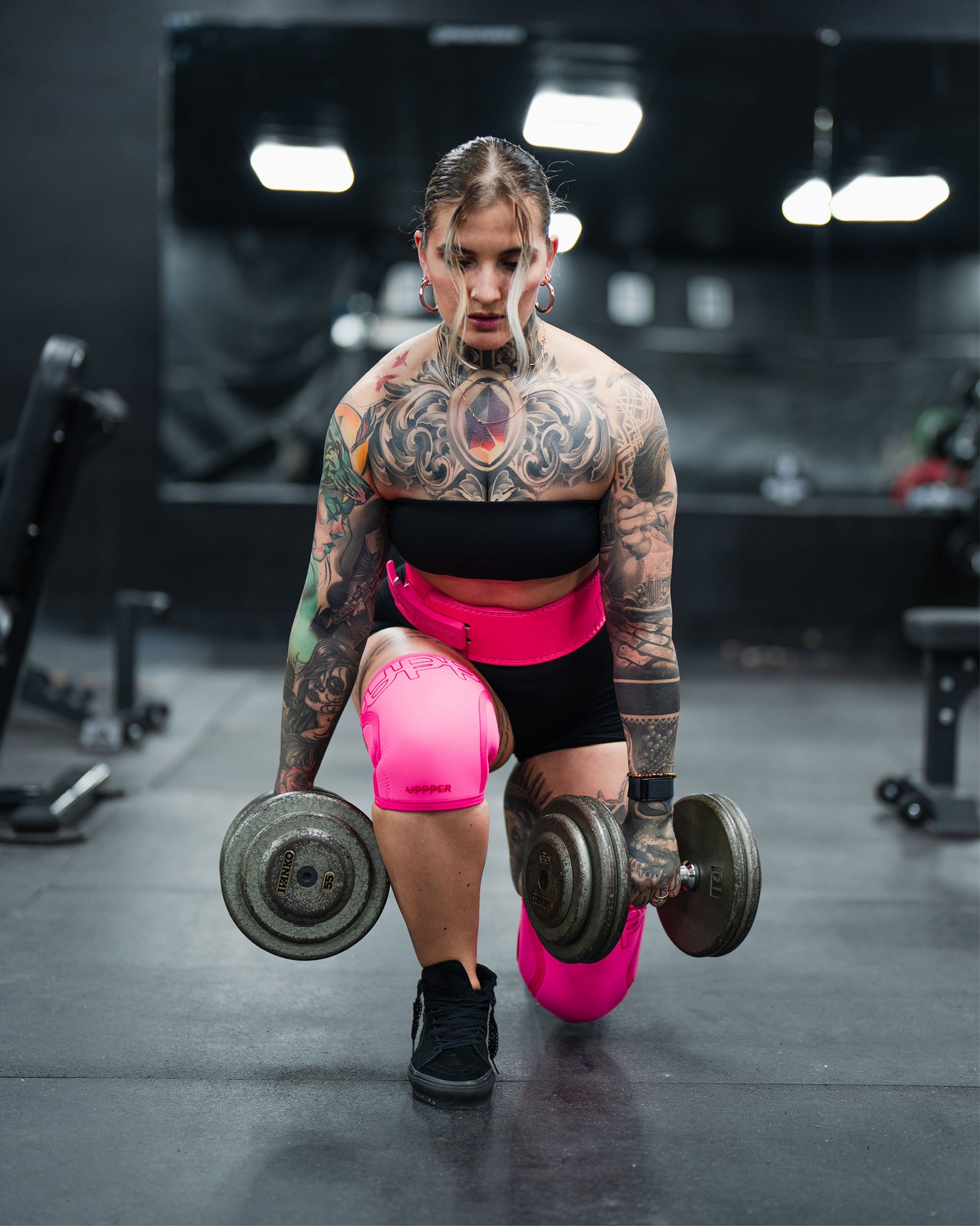 athlete wearing neon pink uppper knee sleeve and lever belt during exercise