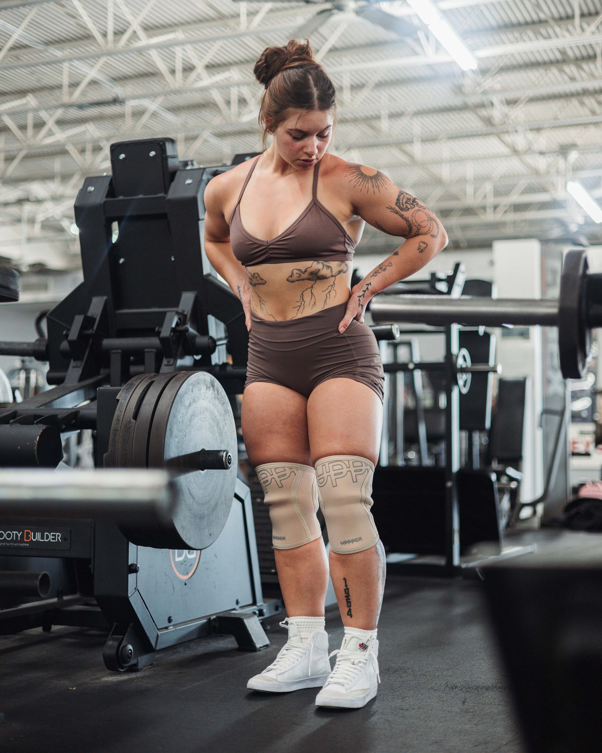 woman in a gym wearing uppper knee sleeves in sail color