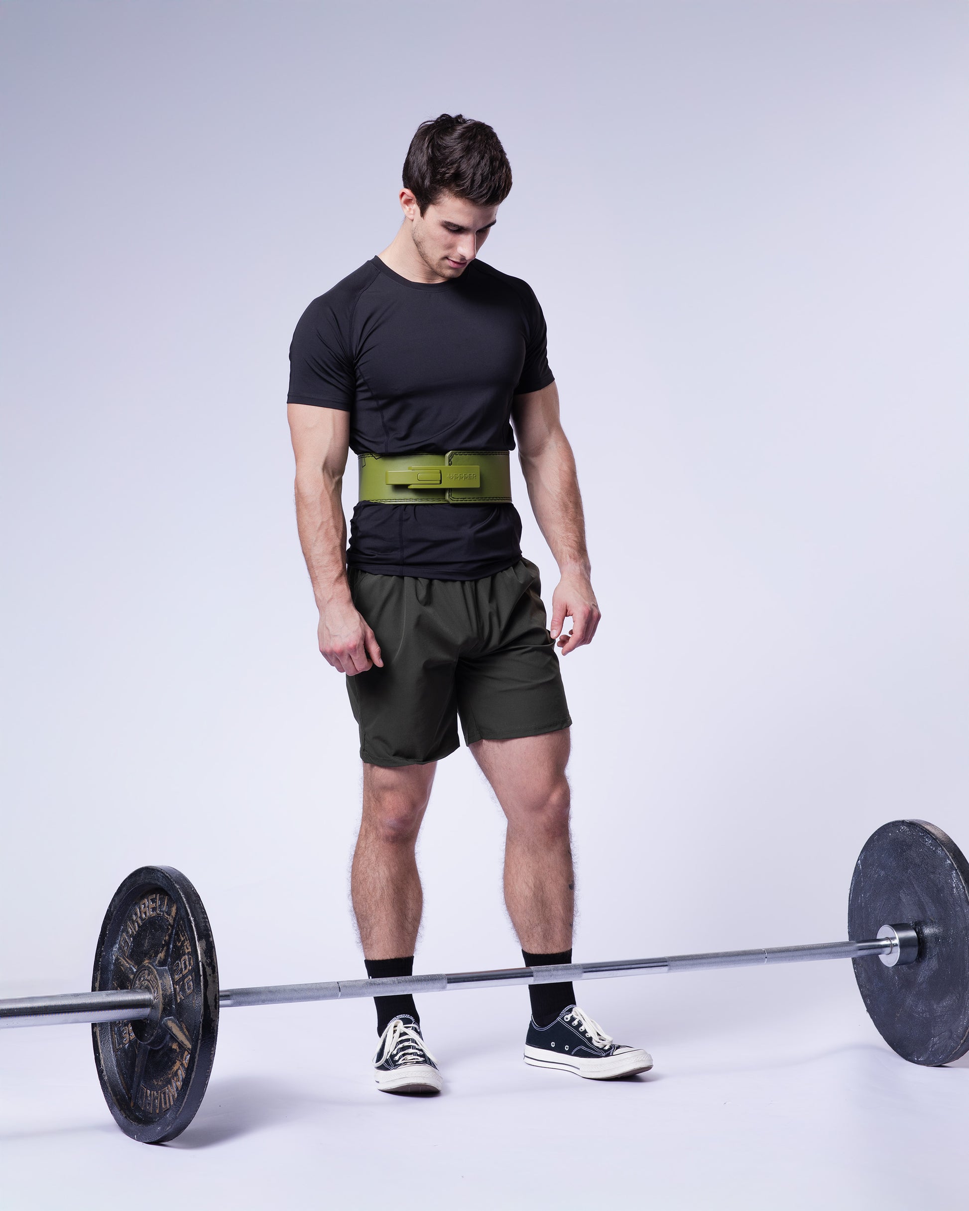 athlete posing in khaki uppper lever belt studio shot on grey background