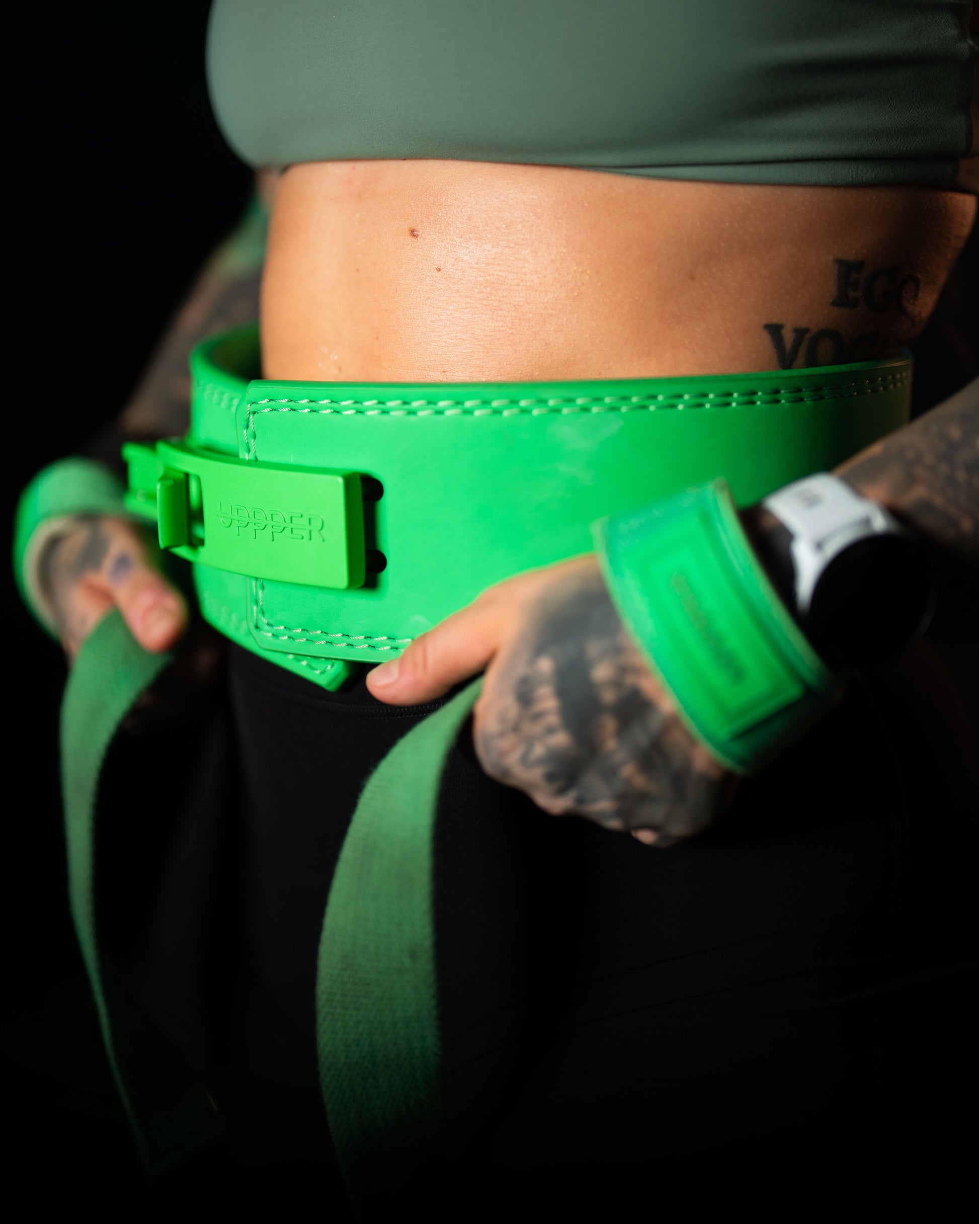 close-up of athlete's waist wearing neon green uppper lever belt on dark background