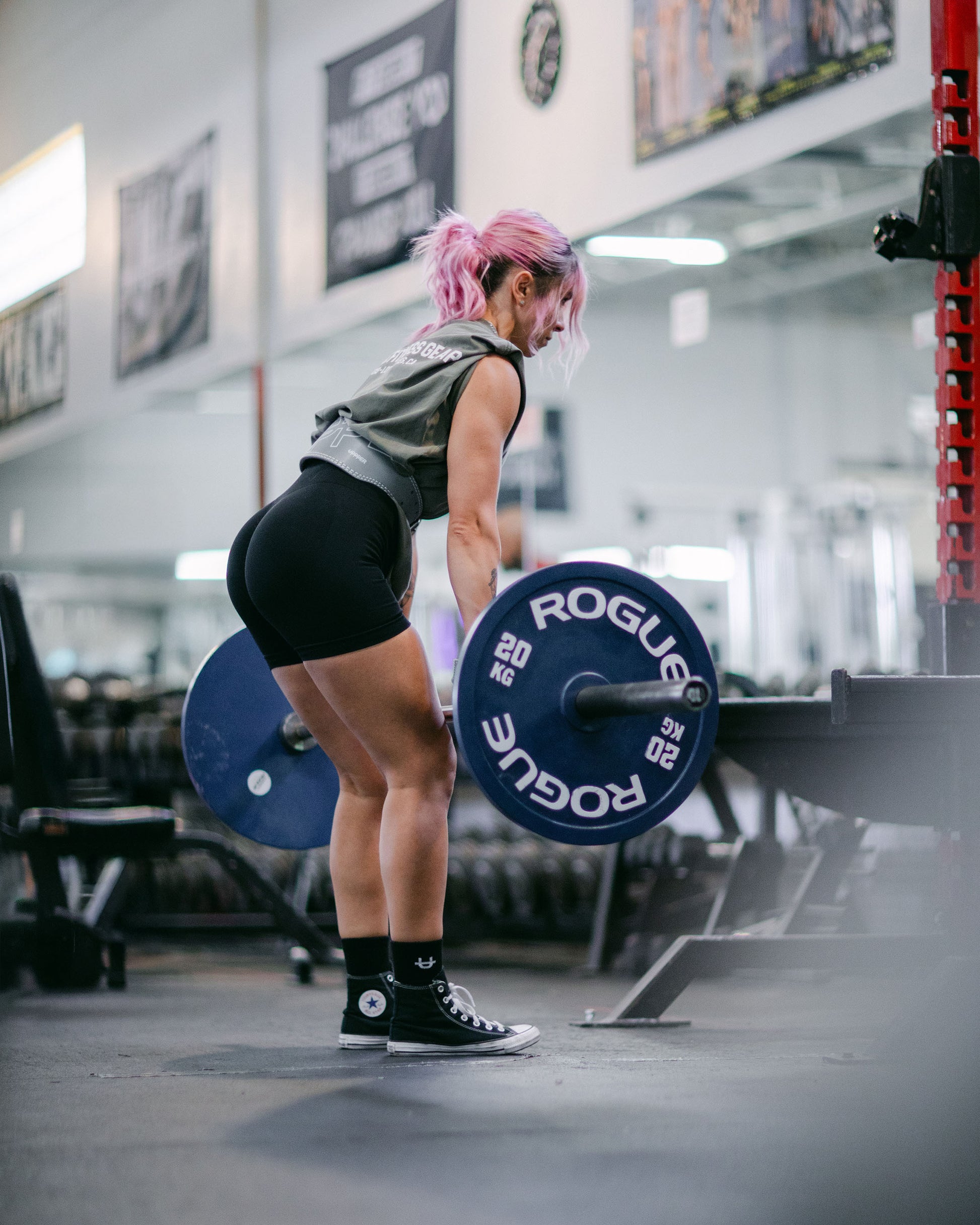 person lifting a barbell using grey uppper lifting belt in a gym setting