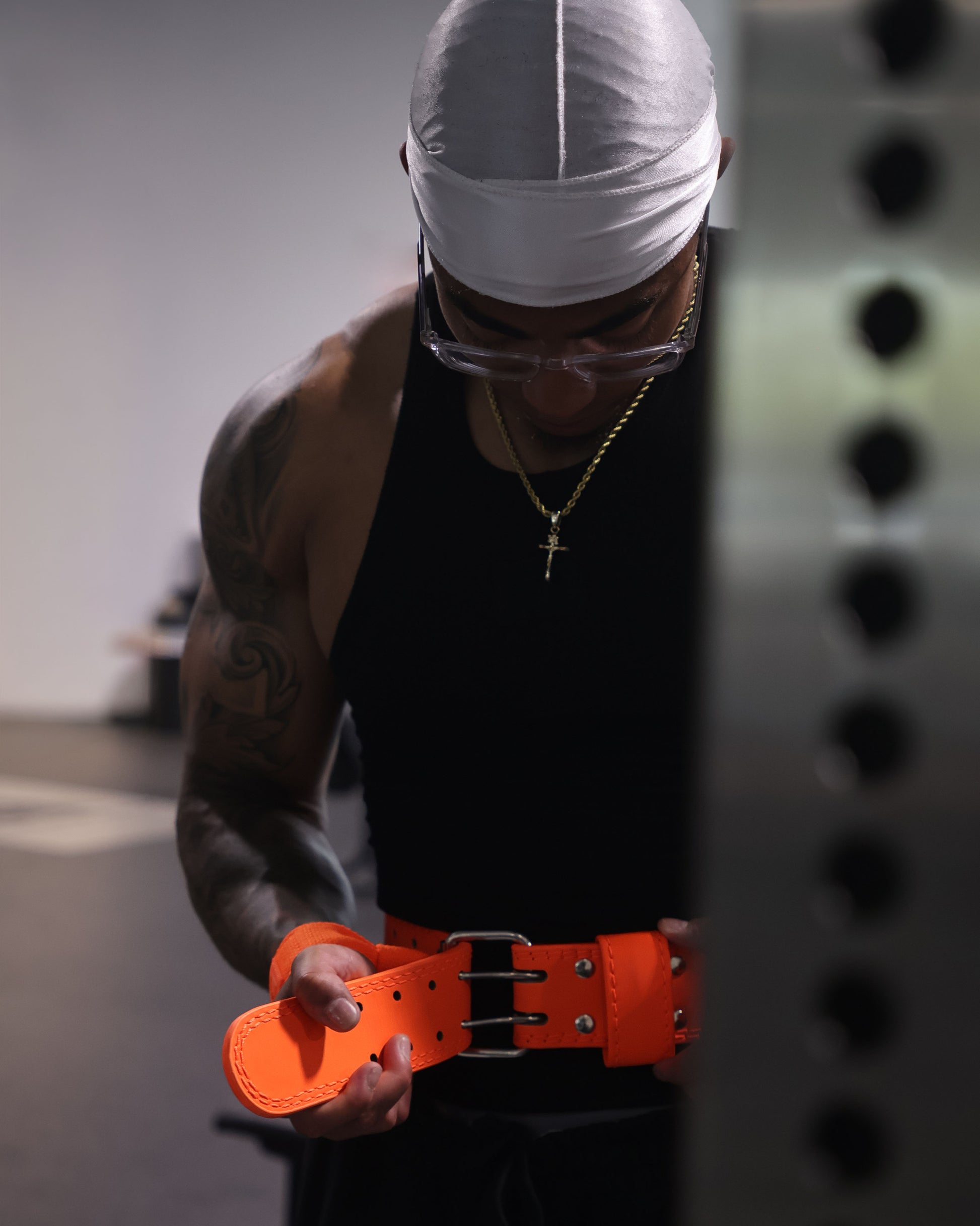 athlete putting on neon orange uppper lifting belt showing prong buckle