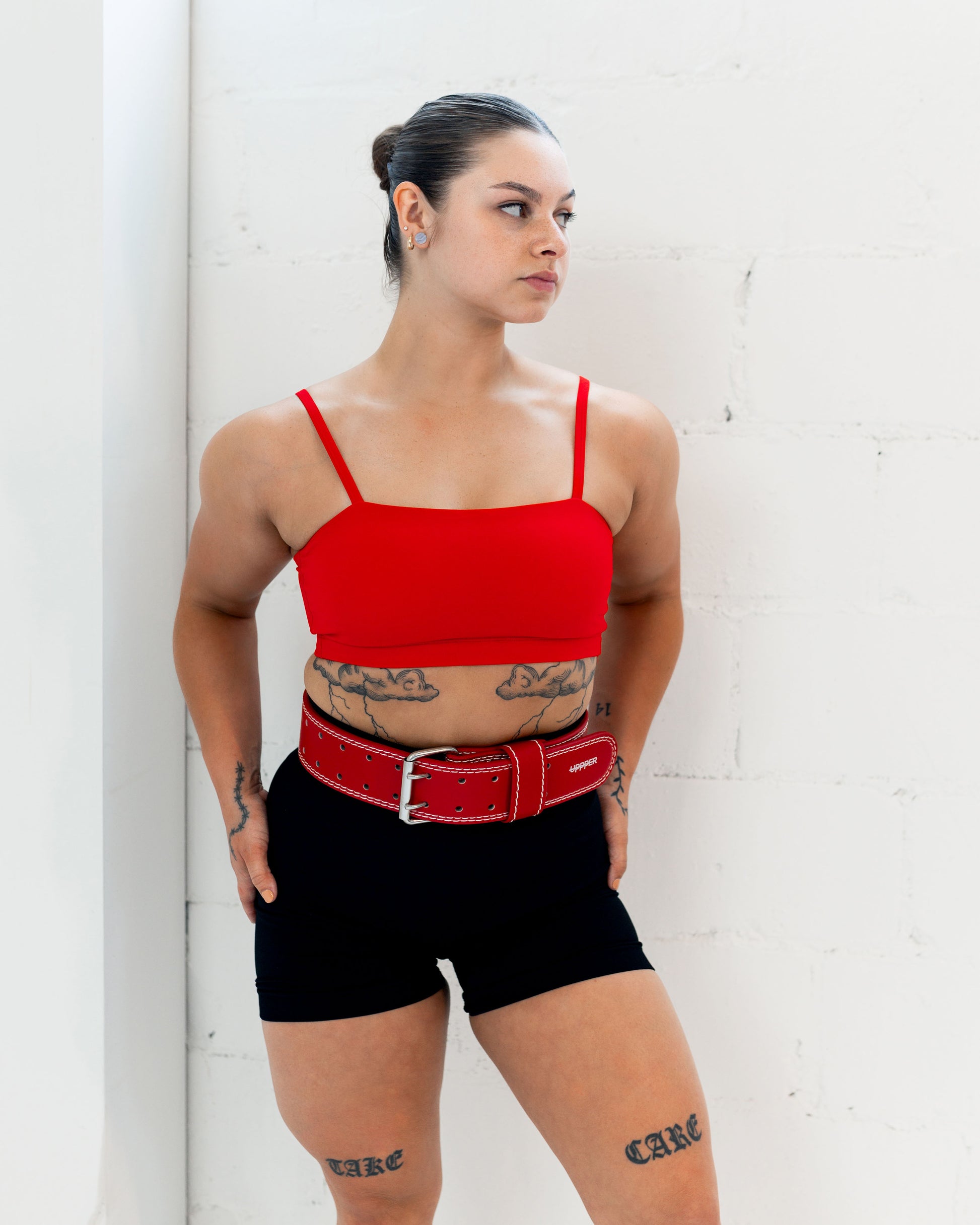 woman posing in a red uppper lifting belt on white background