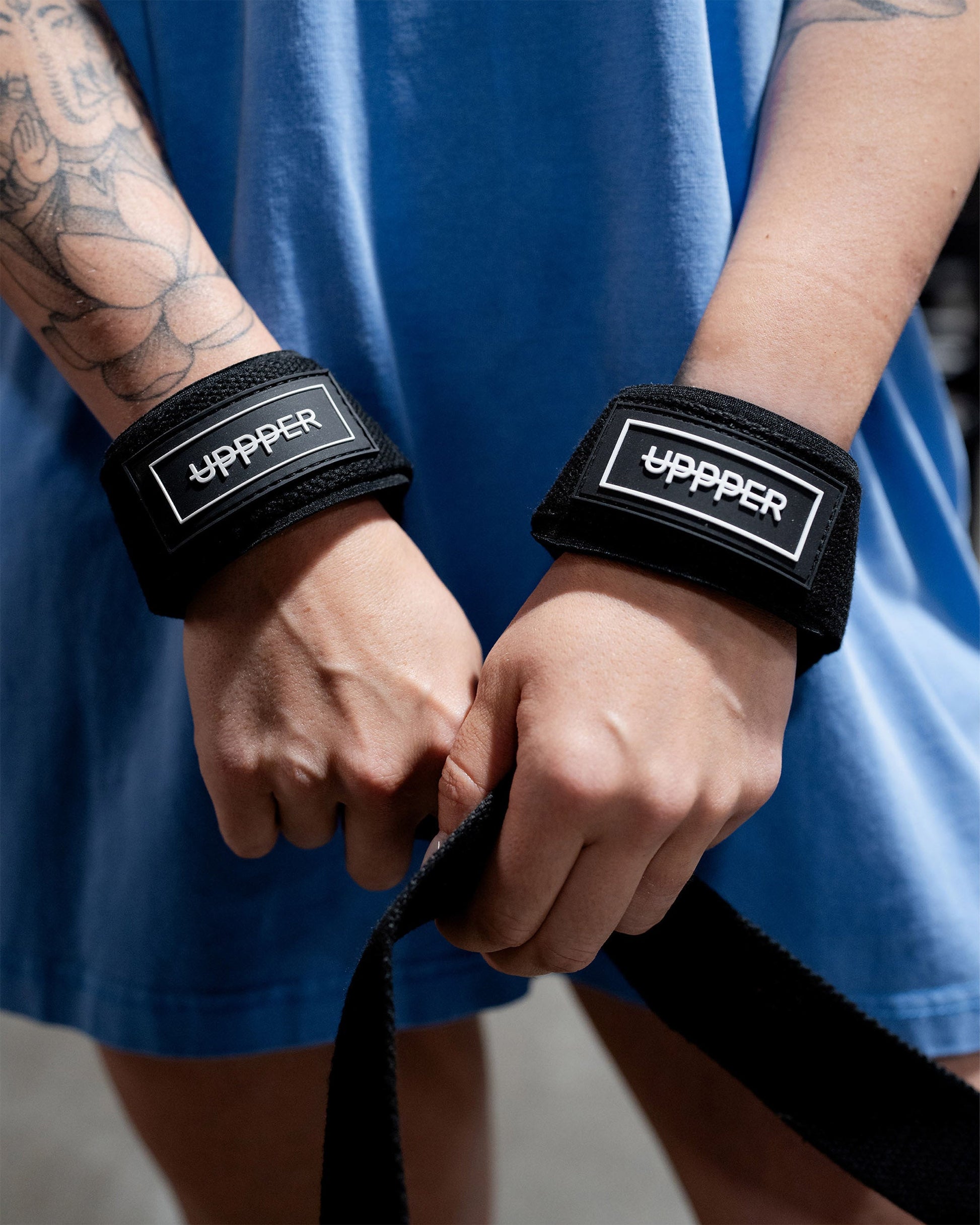black uppper lifting straps looped around wrists showing strap logo