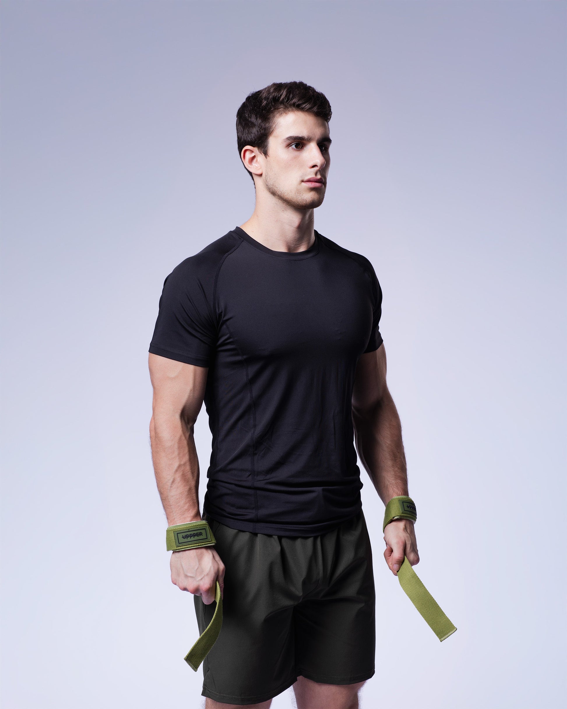 athlete posing in khaki uppper lifting strap on grey background