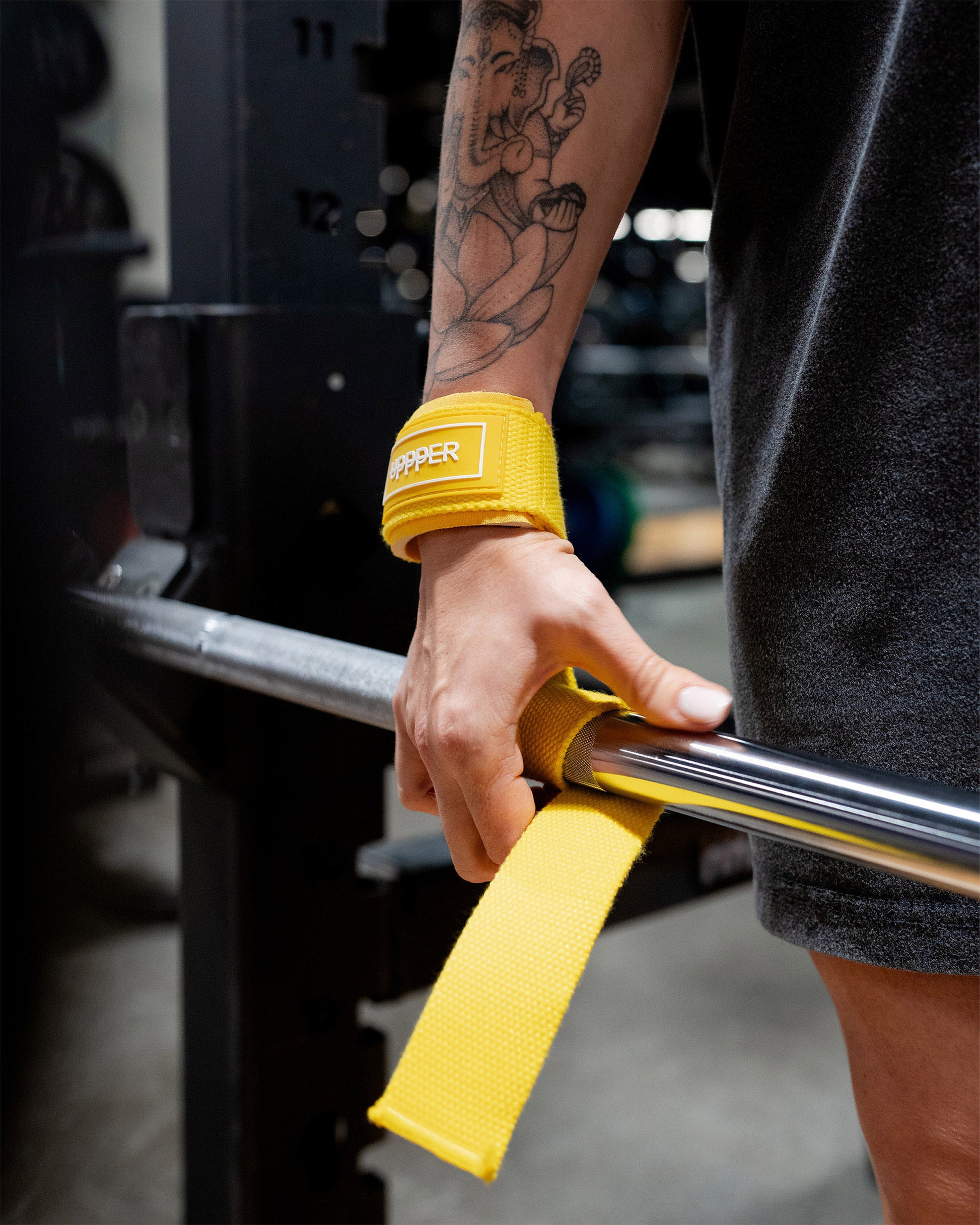 model wearing yellow uppper lifting straps looped around bar