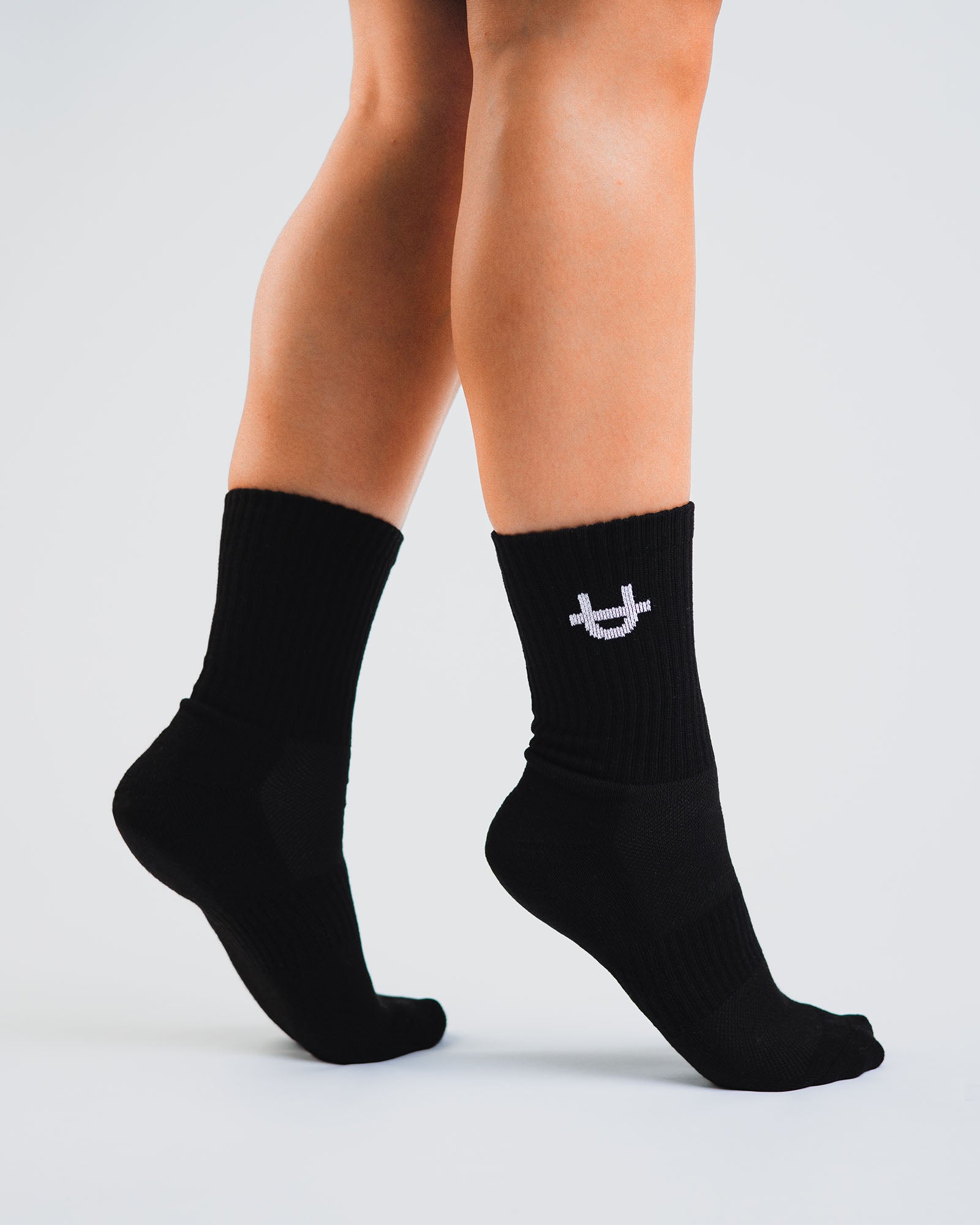 black uppper crew socks worn on feet showing fit and logo detail