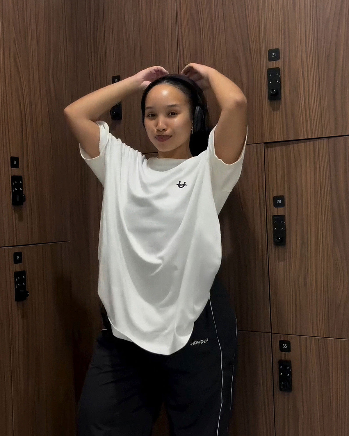 woman with arms raised wearing white oversized uppper t-shirt showing relaxed drape