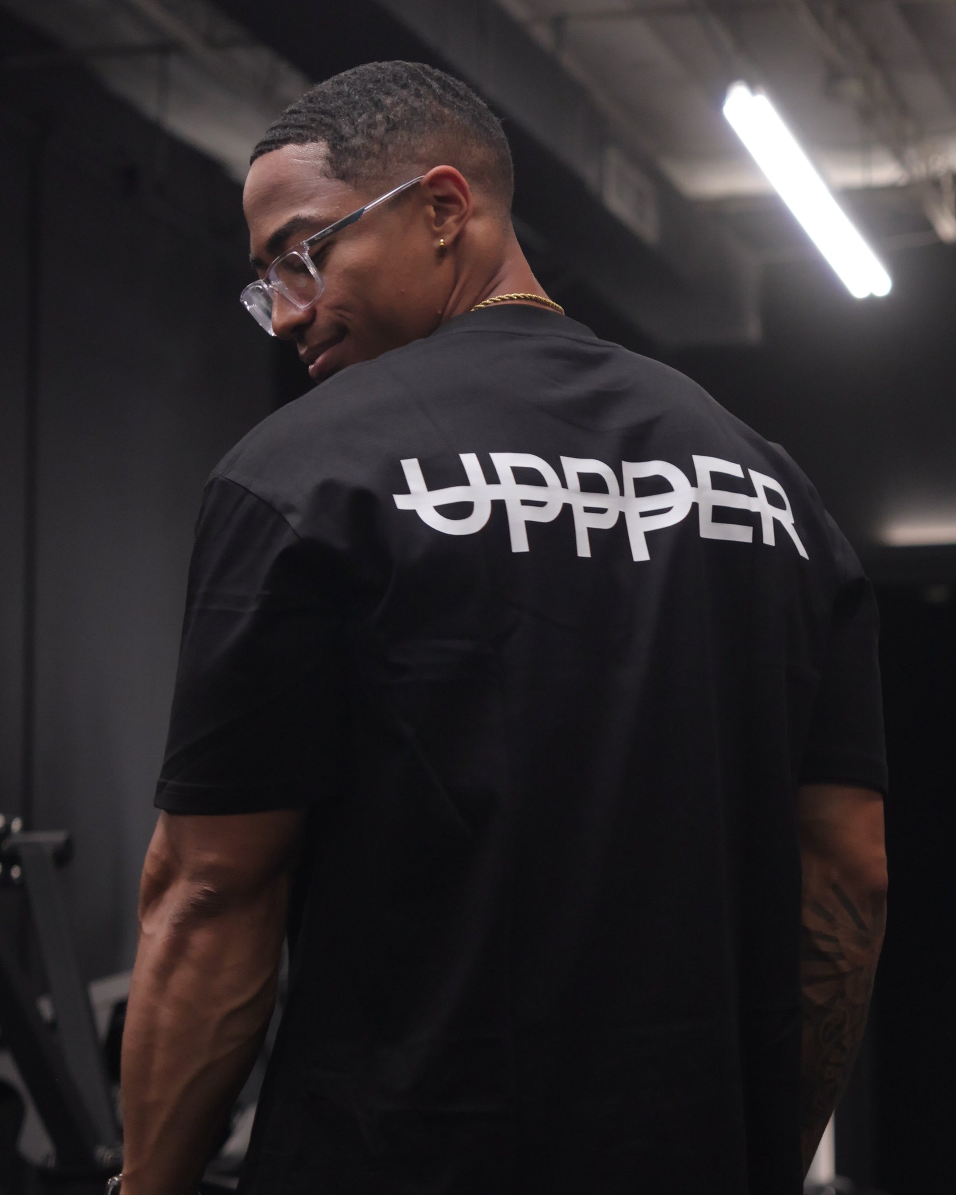 athlete from behind showing white uppper logo on back of black core t-shirt