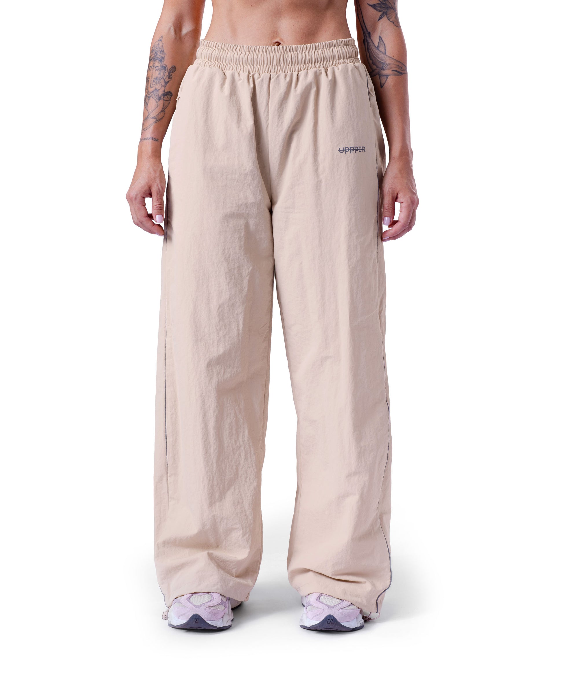 front of tan uppper track pants with reflective stripe detail on white background