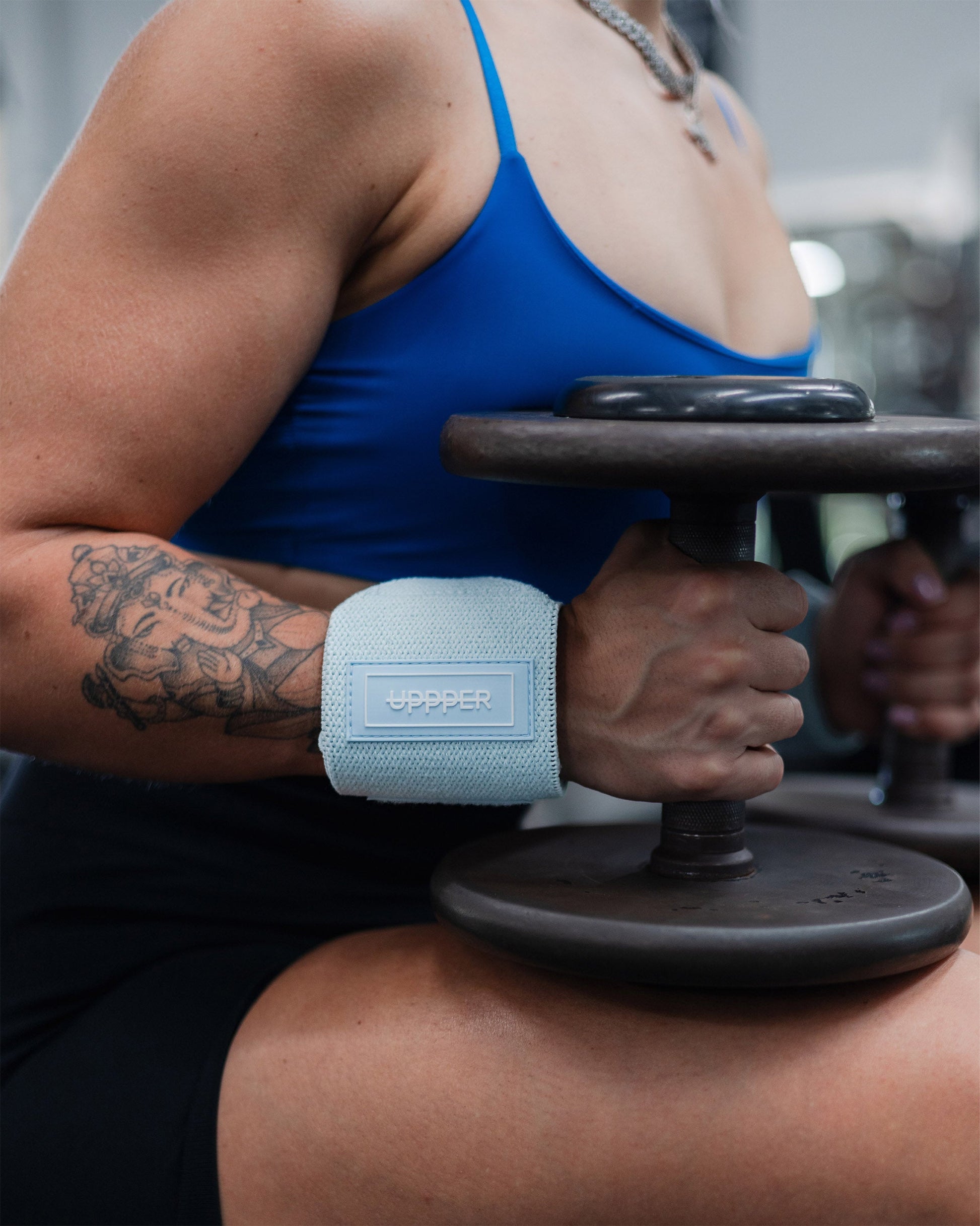 athlete wearing baby blue uppper wrist wraps while holding dumbbell