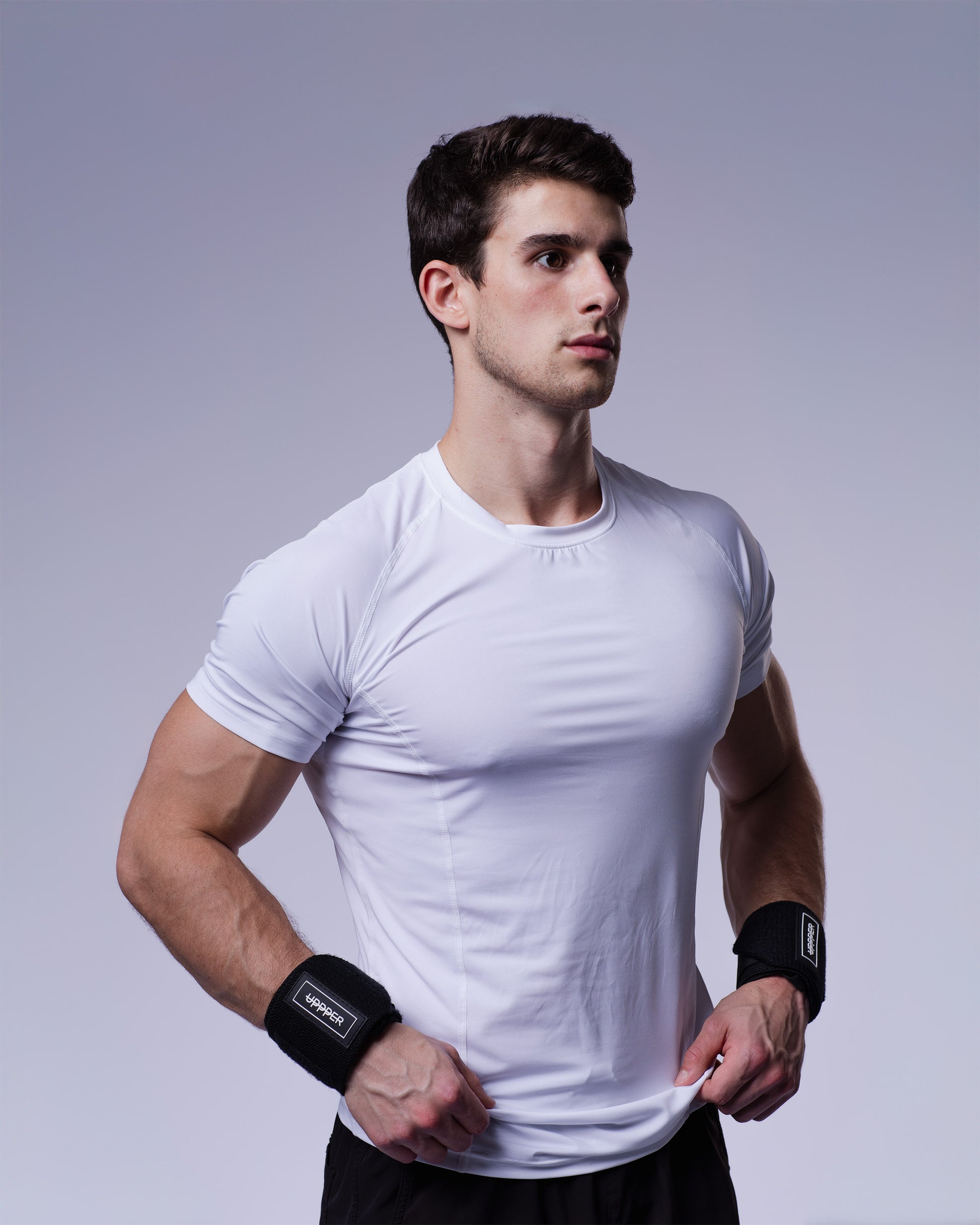man posing in black uppper wrist wraps on grey background