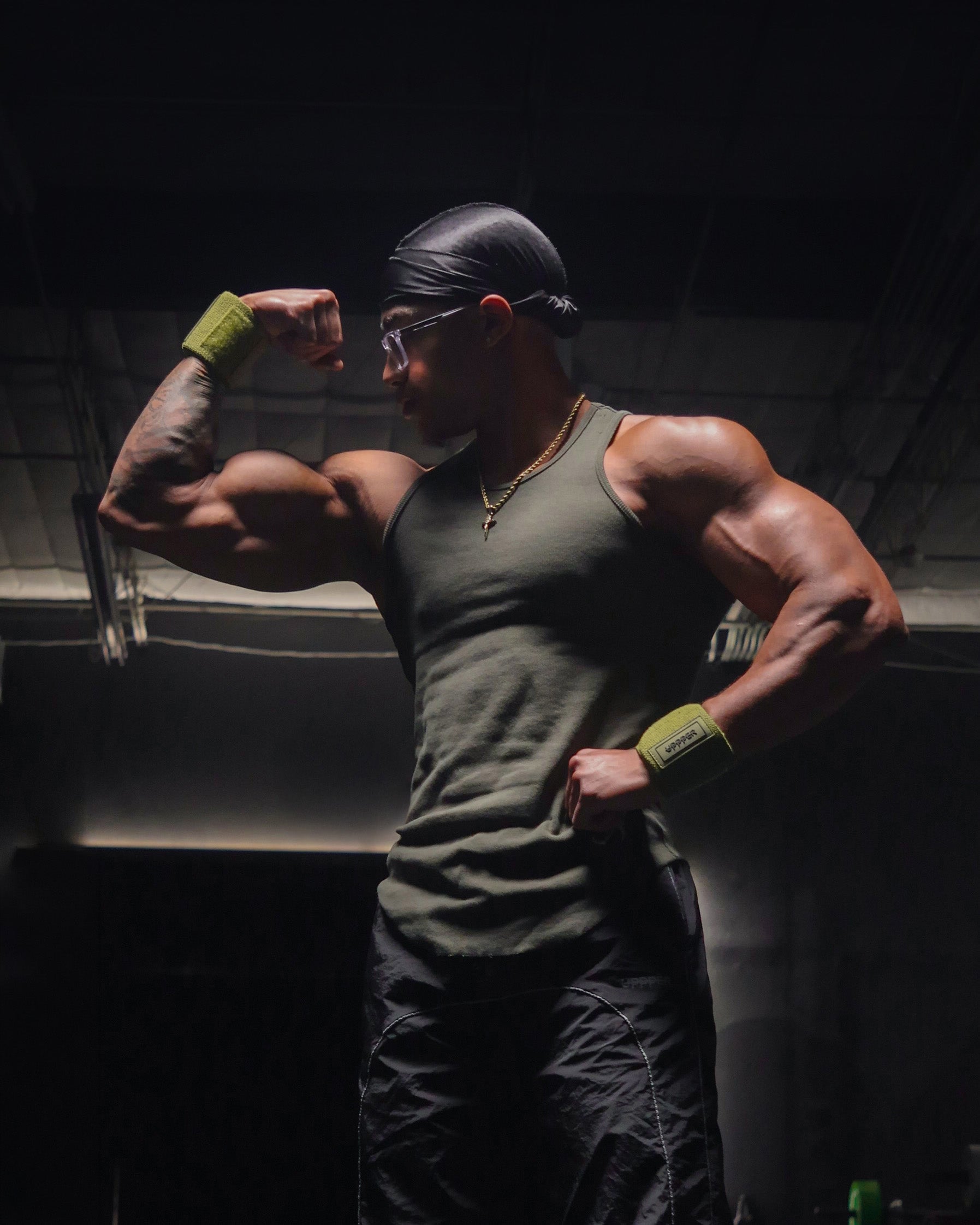man posing in gym with khaki uppper wrist wraps worn on wrists