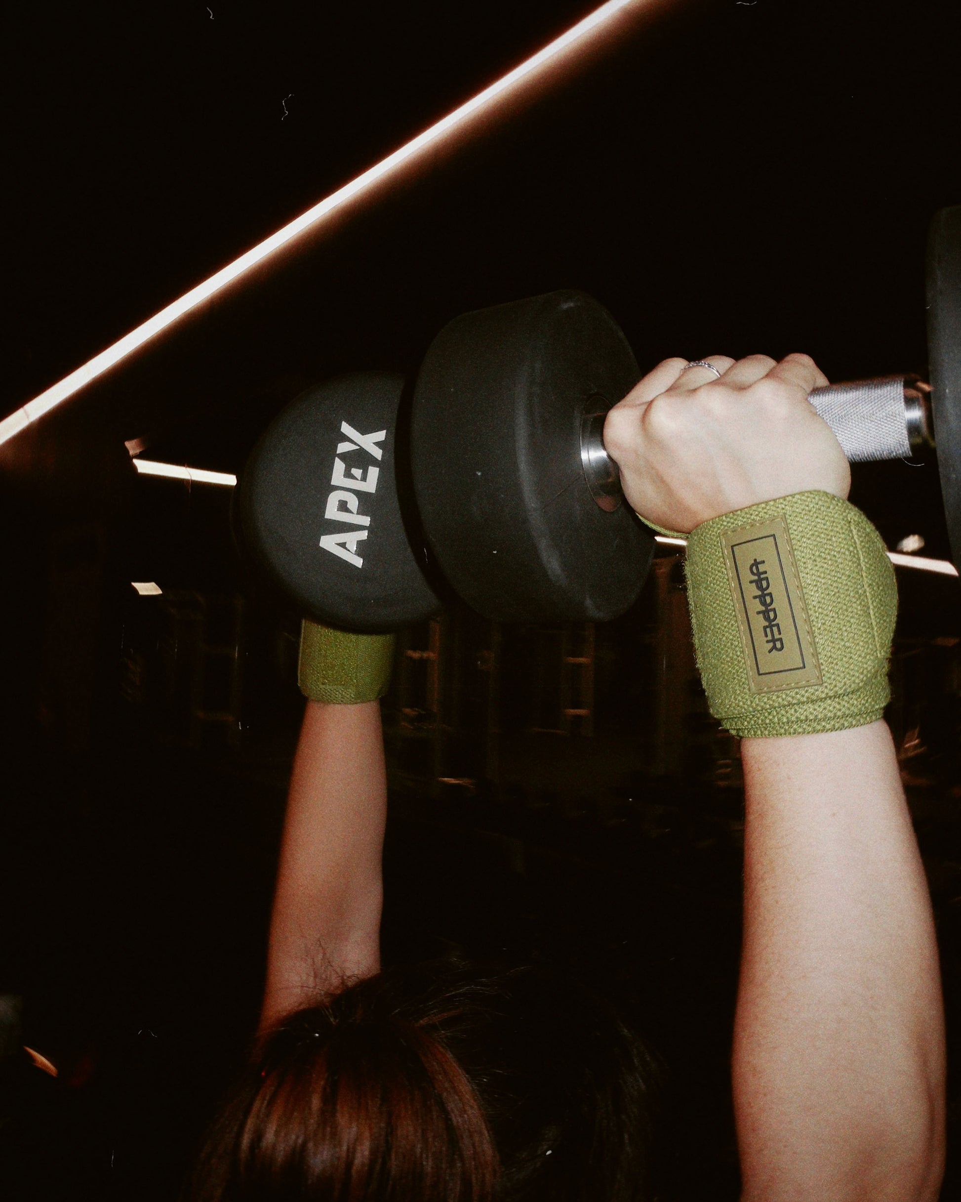 athlete wrists during exercise with dumbbells wearing khaki uppper wrist wraps