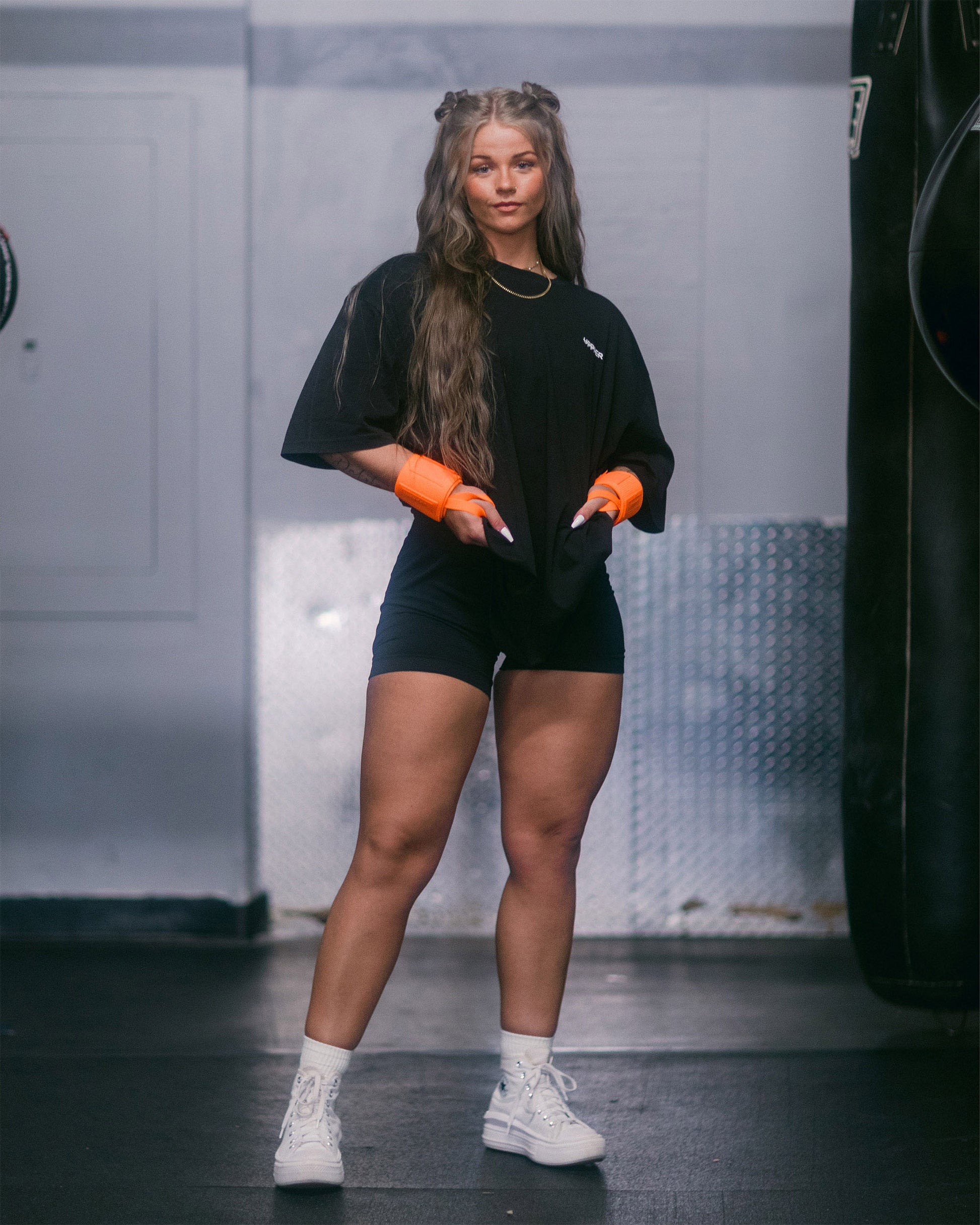 athlete posing in neon orange uppper wrist wrap in gym
