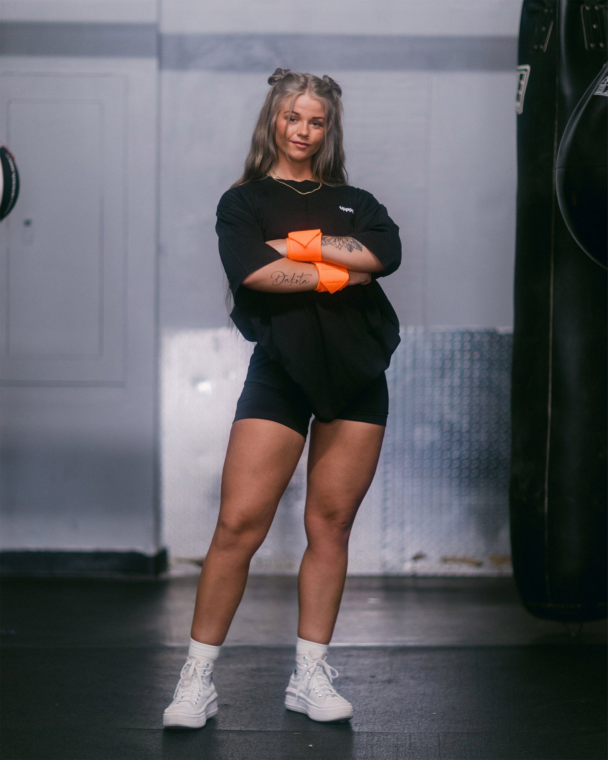 model posing in neon orange uppper wrist wraps shown wrapped around wrists