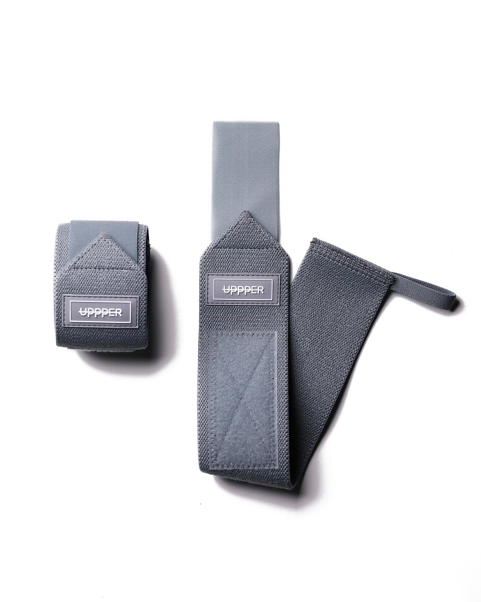 pair of grey uppper wrist wraps one rolled and one extended on white background