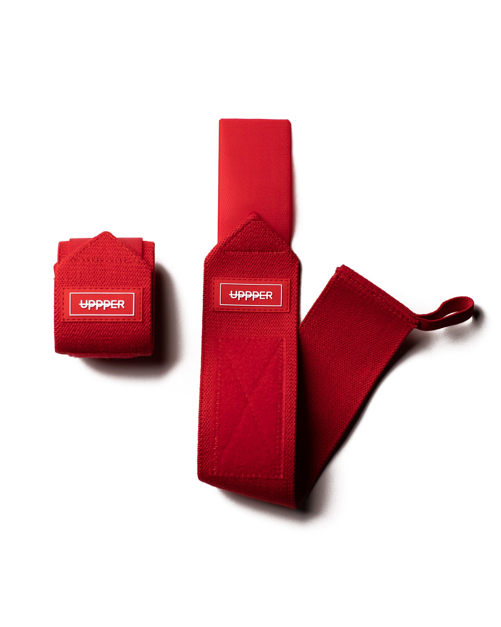 pair of red uppper wrist wraps one rolled and one extended on white background